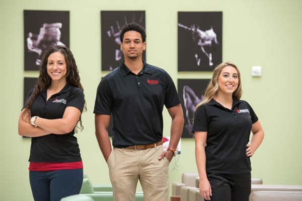 happy physical therapy students standing in front of various x-rays